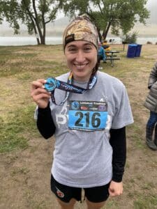 Melissa smiling and holding triathlon metal